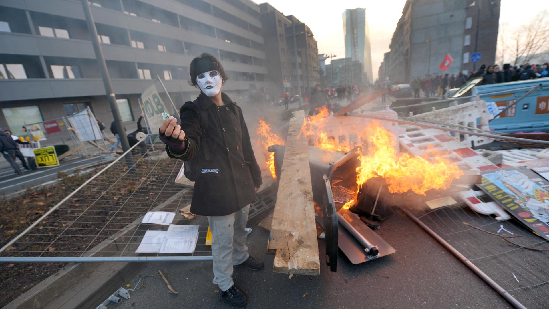 Ein Blockupy-Aktivist demonstriert anlässlich des EZB-Neubaus vor einer brennenden Barrikade in Frankfurt.
