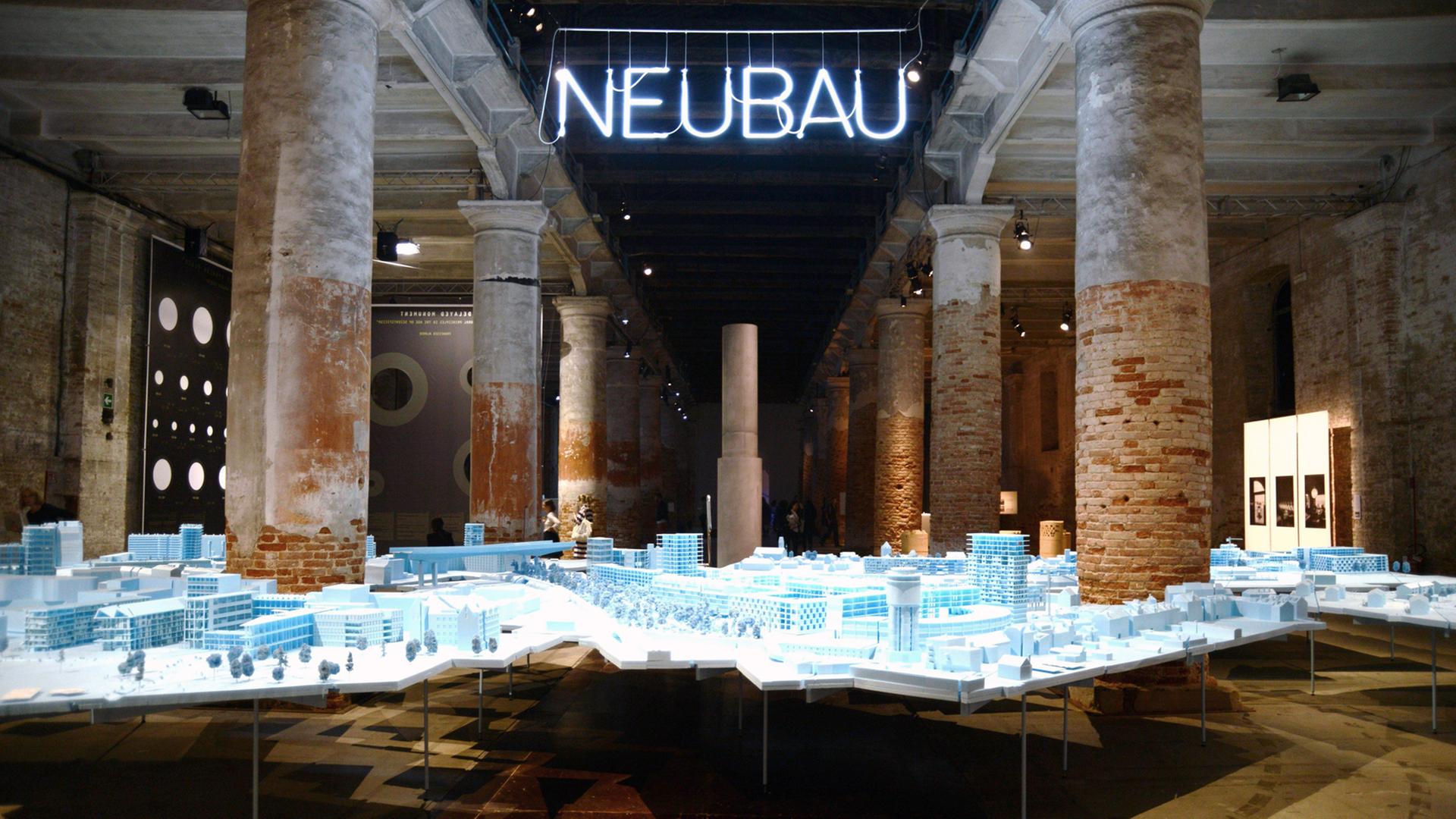 Die 15. Biennale der Architektur in Venedig läuft vom 28.05. bis 27.11.2016. Zu sehen ist eine Achitekturinstallation, darüber hängt der Schriftzug "Neubau" als Neonröhre