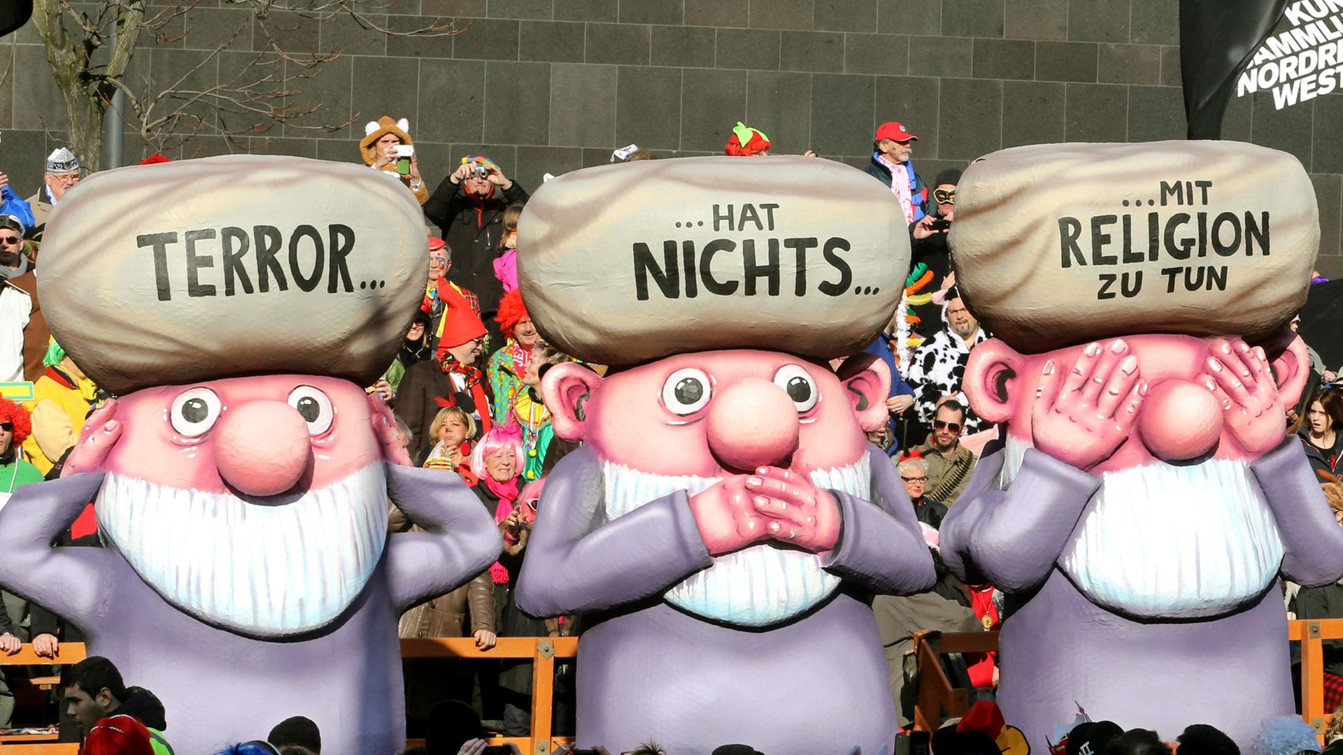Ein Karnevalswagen beim Rosenmontaqgszug in Düsseldorf zeigt das Motiv "Terror hat nichts mit Religion zu tun".