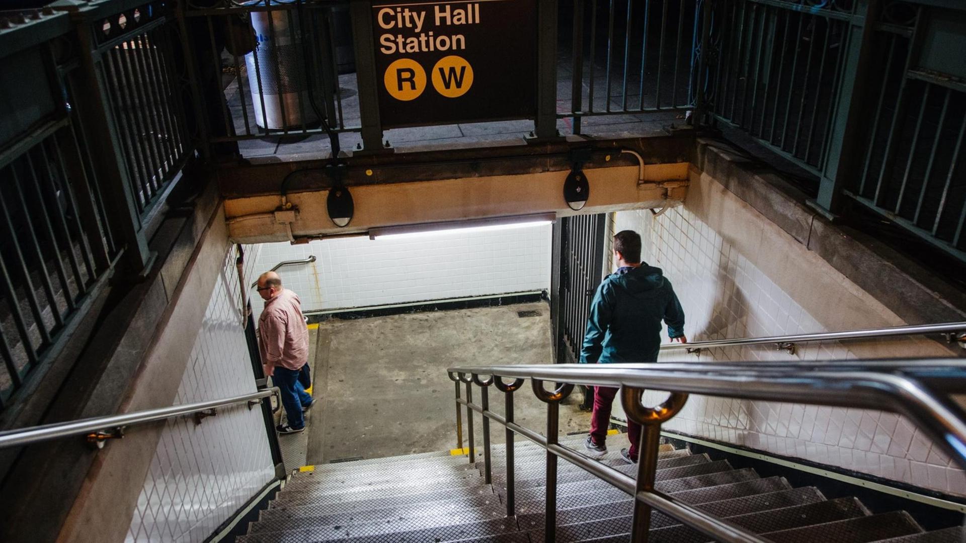 Eine U-Bahn-Station in Manhattan, Menschen gehen die Treppe zum Gleis hinunter.