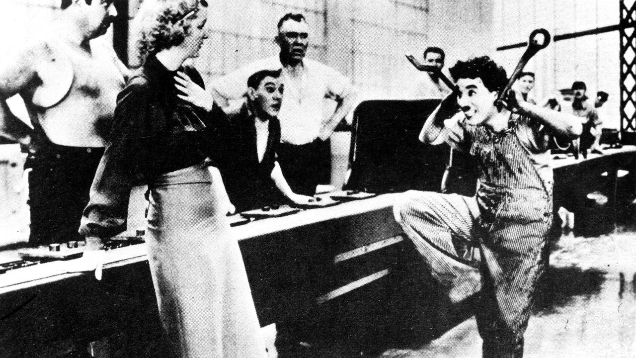 MODERNE ZEITEN, USA 1936, ist einer der großen Klassiker der Filmgeschichte, in dem der vermeintlich moderne Arbeitsalltag, die Maschine über den Menschen stellt. Szene: Durch die Monotonie seiner Arbeit wird Charlie (CHARLIE CHAPLIN) in den Wahnsinn getrieben.