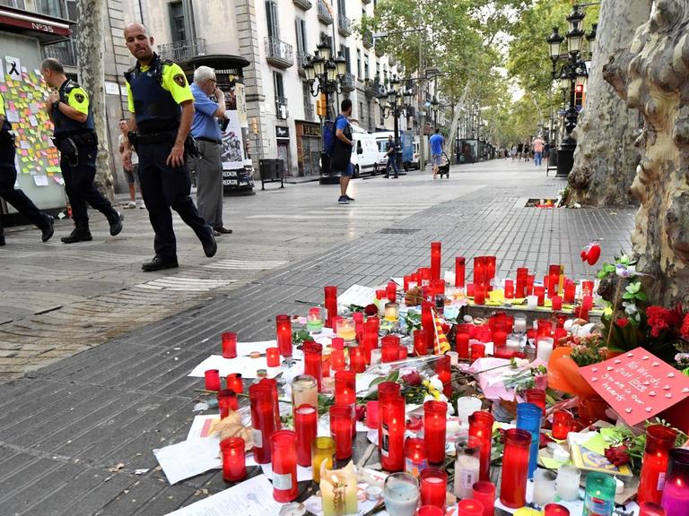 Polizisten patrouillieren entlang des Boulevards Las Ramblas in Barcelona. Auf der Straße stehen Kerzen, die an die Opfer des Terroranschlags erinnern.