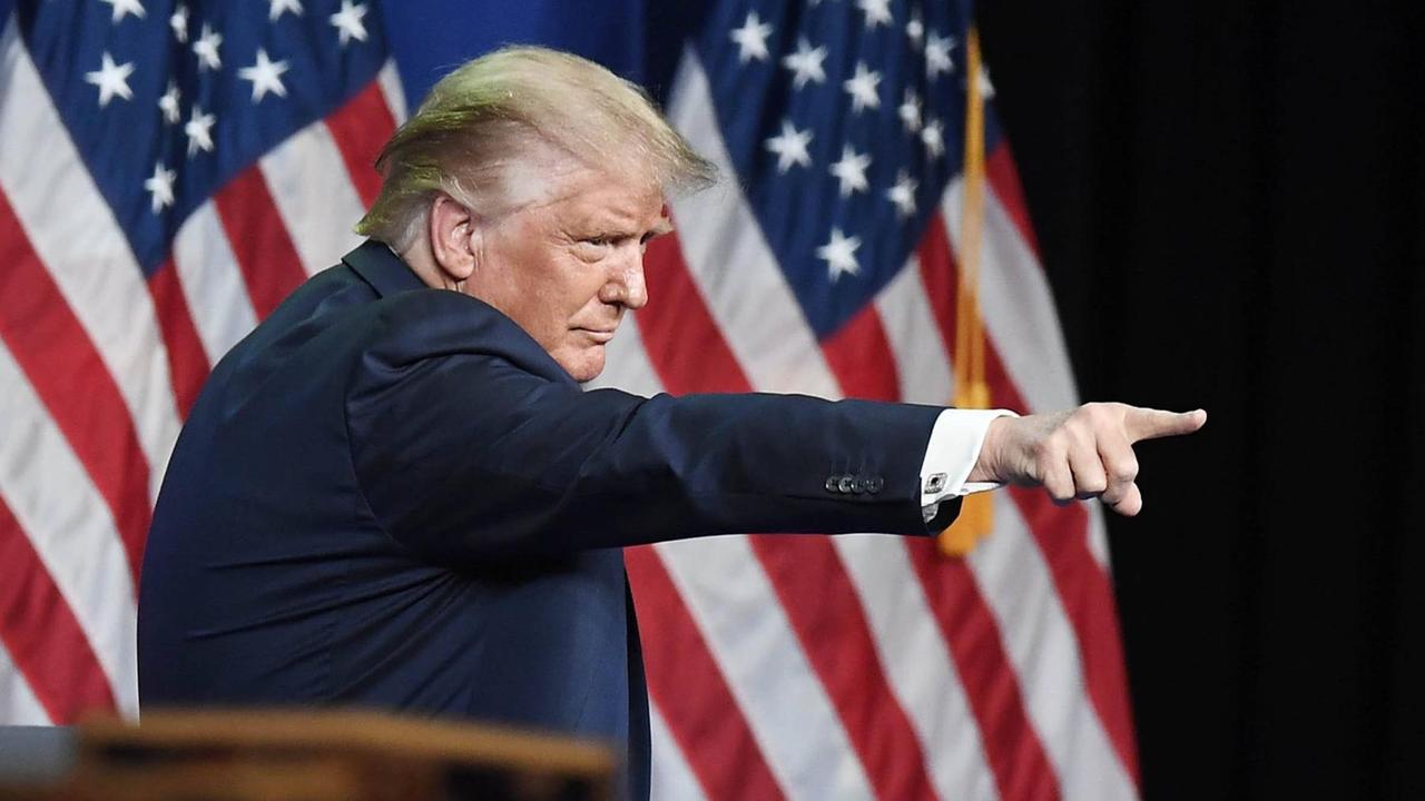 Trump zeigt mit dem Finger auf jemanden, den man nicht auf dem Foto sehen kann. 