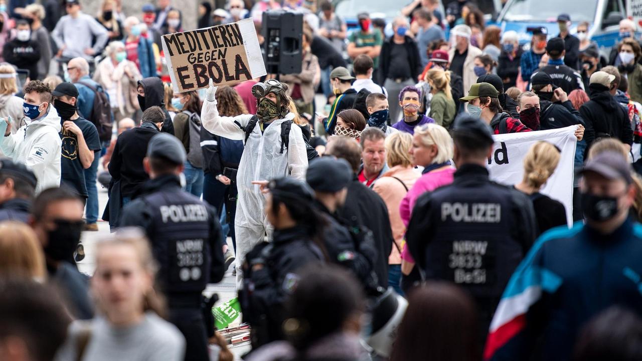 Ein Mann hält während einer Demo ein Schild mit der Aufschrift "Meditieren gegen Ebola"