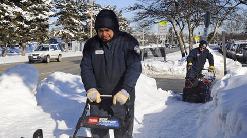 Ein Mann räumt mit einem elektrischen Gerät Schneemassen zu Seite
