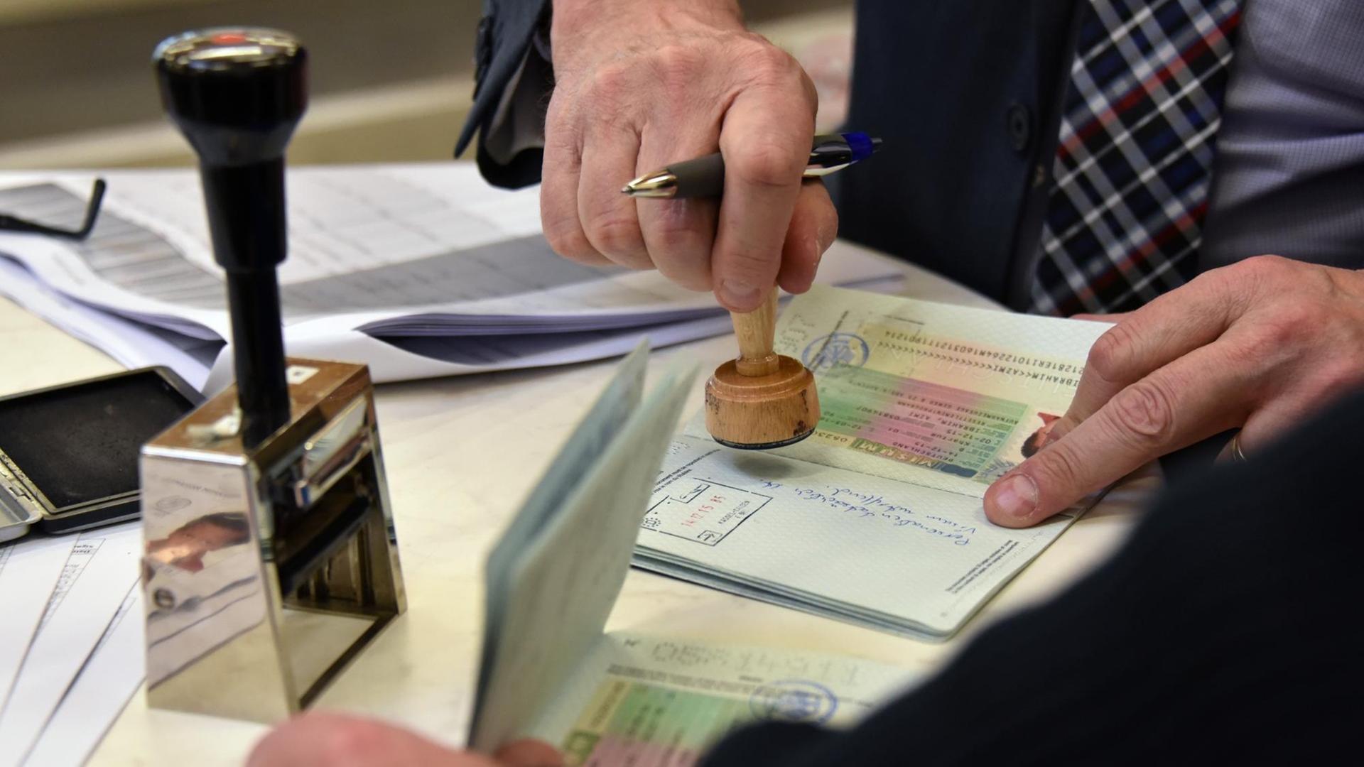 Ein Beamter stempelt bei der Passkontrolle Papiere ab.