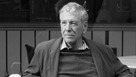 Der israelische Schriftsteller Amos Oz sitzt auf einer Bank und blickt in die Ferne