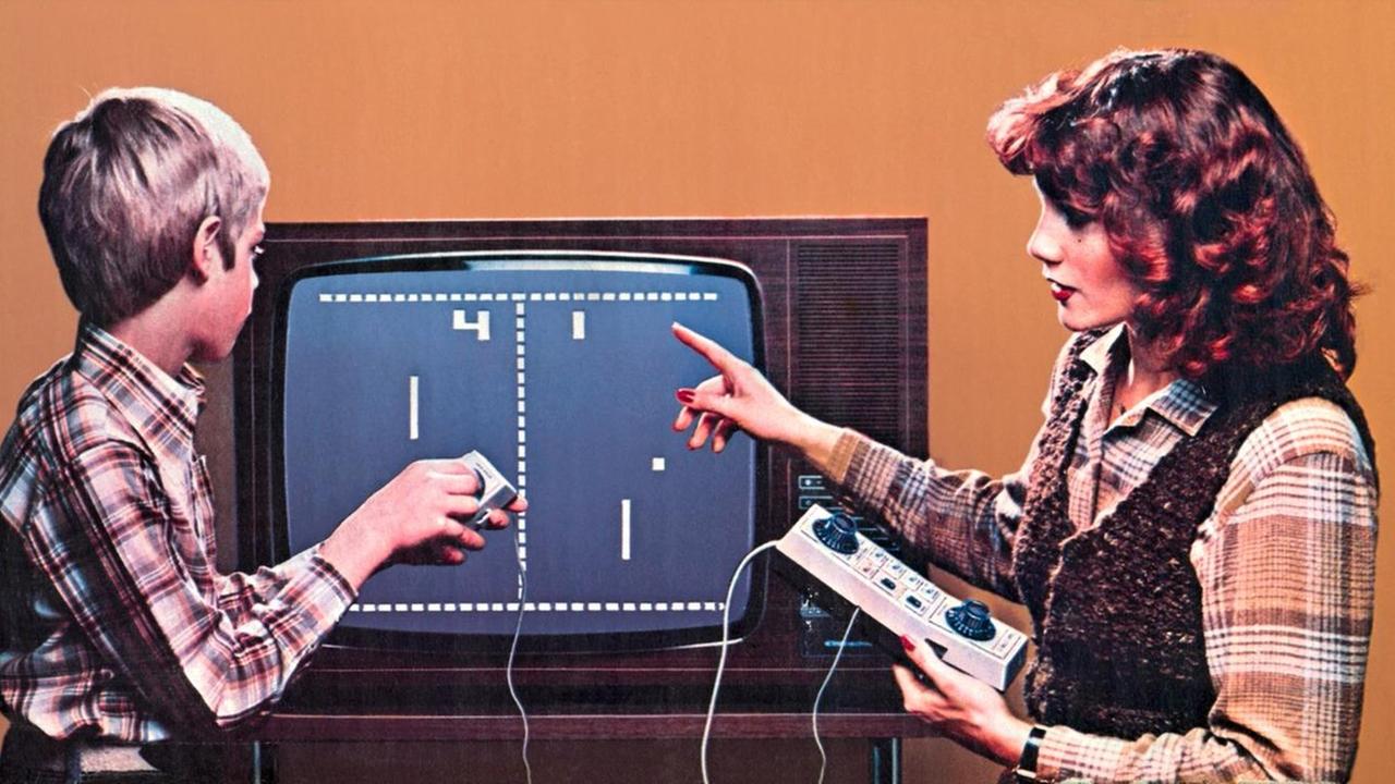 Eine Frau und ein Junge sitzen vor einem Monitor und spielen ein Spiel.