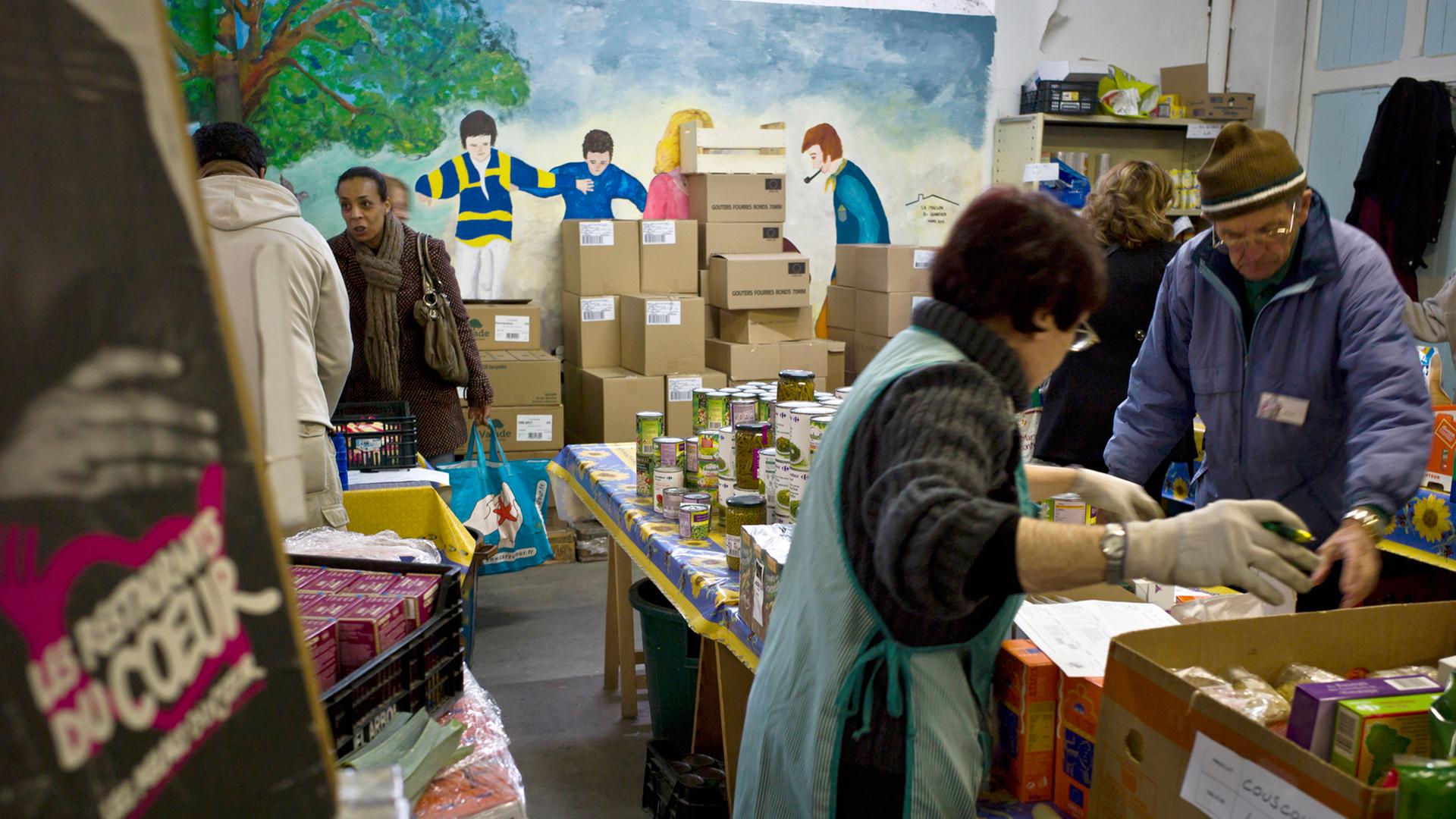 Ehrenamtliche verteilen Kleidung und Lebensmittel an Bedürftige in einer Einrichtung der französischen Initiative "Resto du Coeur"