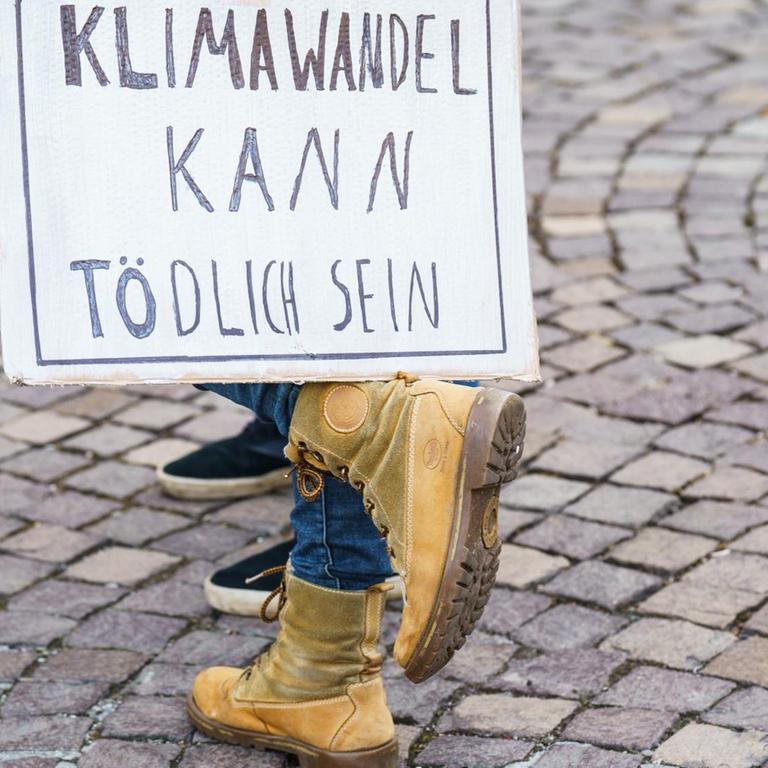 Eine Teilnehmerin des Globalen Fridays for Future Streiks stellt auf ihrem Fuß ein Schild "Klimawandel kann Tödlich sein" ab