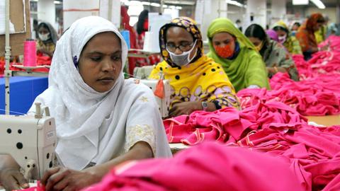 FRauen und Männer arbeiten unter schweren Bedingungen in der Textilfabrik 'One Composite Mills' in Gazipur an Nähmaschinen.