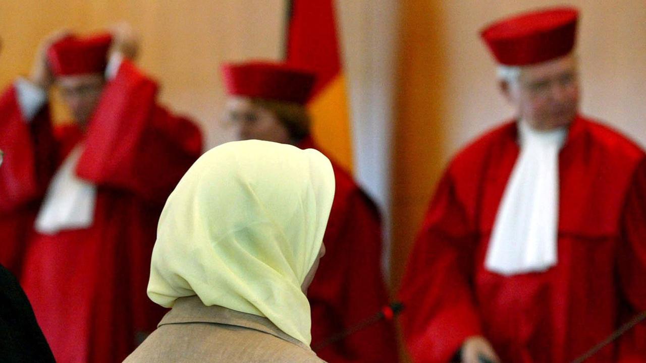 Fereshta Ludin, muslimische Lehrerin und Beschwerdeführerin im Kopftuch-Streit, sitzt am 24.9.2003 nach der Urteilsverkündung im Bundesverfassungsgericht in Karlsruhe vor den Richtern (l-r) Rudolf Mellinghoff, Lerke Osterloh und Hans-Joachim Jentsch. Die Bundesländer dürfen muslimischen Lehrerinnen das Kopftuchtragen im Unterricht verbieten. Dazu müssen sie jedoch nach dem Urteil des Bundesverfassungsgerichts eine "hinreichend bestimmte" gesetzliche Grundlage schaffen. Diese fehlt derzeit in Baden-Württemberg. Das Land habe deshalb mit seiner Ablehnung, Ludin in den Schuldienst zu übernehmen, ihre Religionsfreiheit verletzt, entschieden die Richter.
