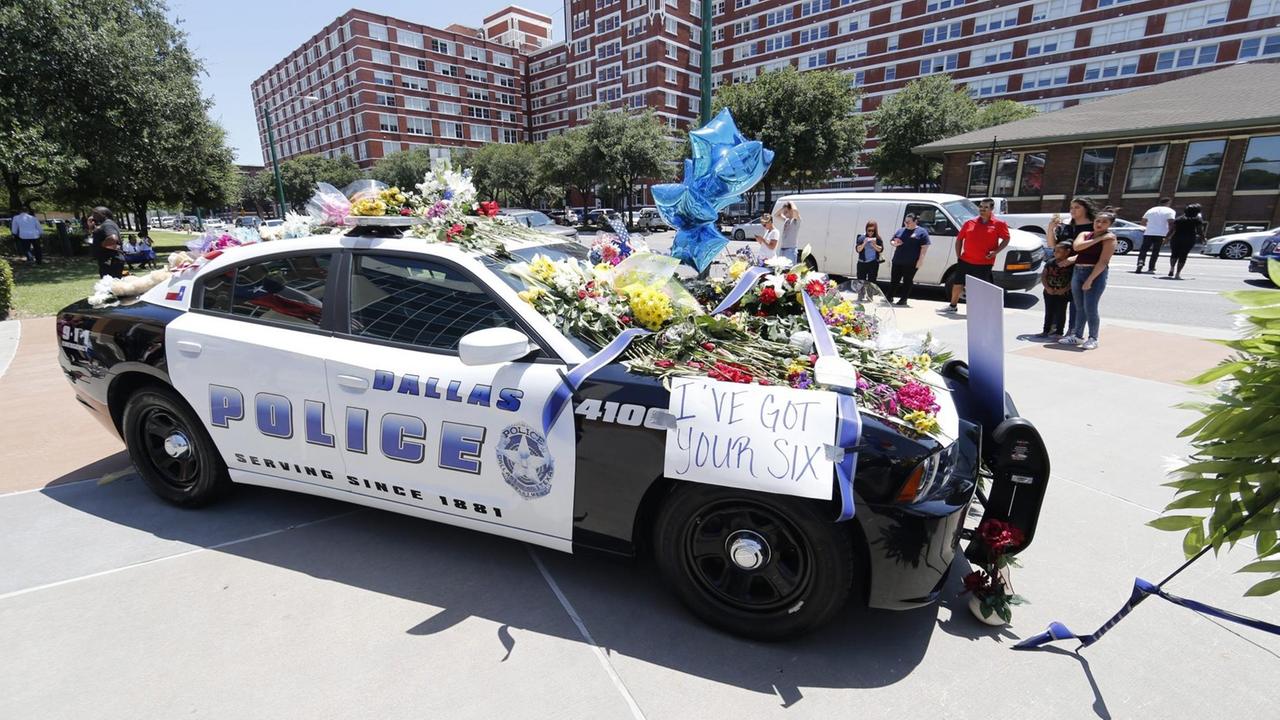 Ein Polizeiauto ist mit Blumen bedeckt nach den Morden an fünf Polizisten am 8.7.2016 in der US-Stadt Dallas.
