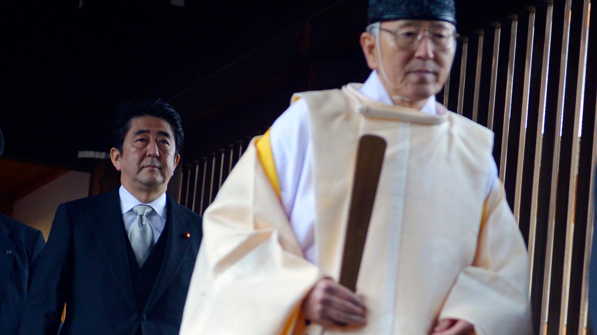 Der japanische Minsterpräsident Shinzo Abe (l.) folgt einem Priester bei seinem Besuch des Yasukuni-Schreins in Tokio am 26. Dezember 2013