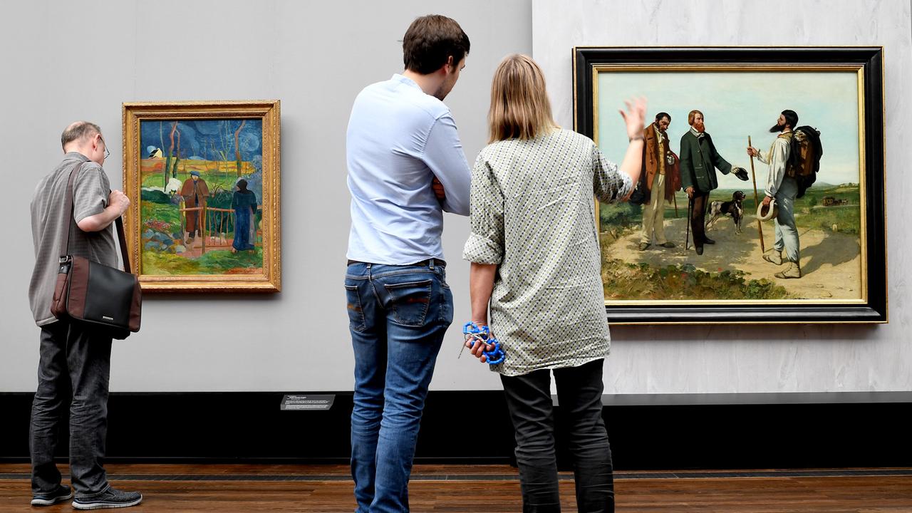 Besucher betrachten die Gemälde "Bonjour Monsieur Gauguin" des Künstlers Paul Gauguin und "Bonjour Monsieur Coubert" des Künstlers Gustave Coubert in der Ausstellung "Wanderlust" in der Alten Nationalgalerie in Berlin.