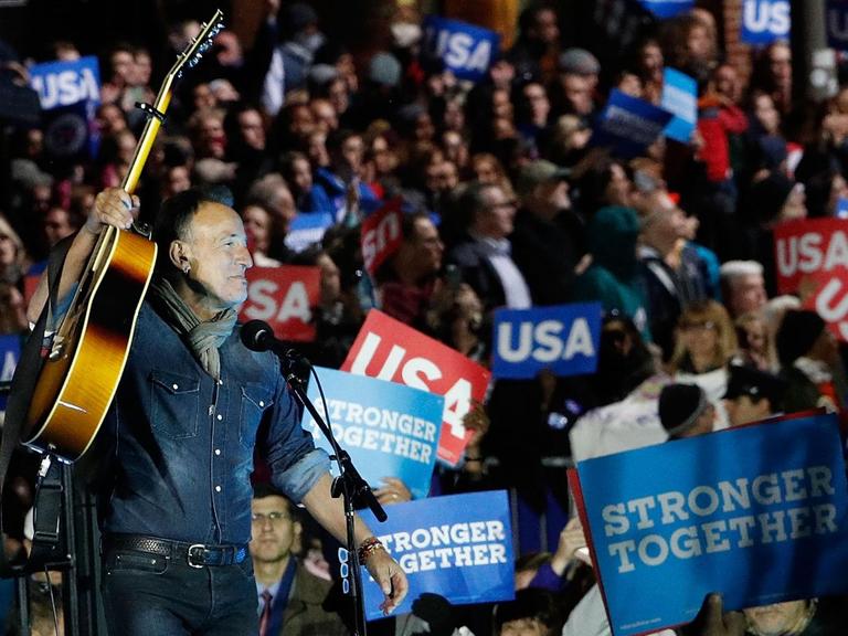 Bruce Springsteen tritt vor den Wählern von Hillary Clinton auf und hält seine Gitarre zur Begrüßung in die Höhe. (2016)