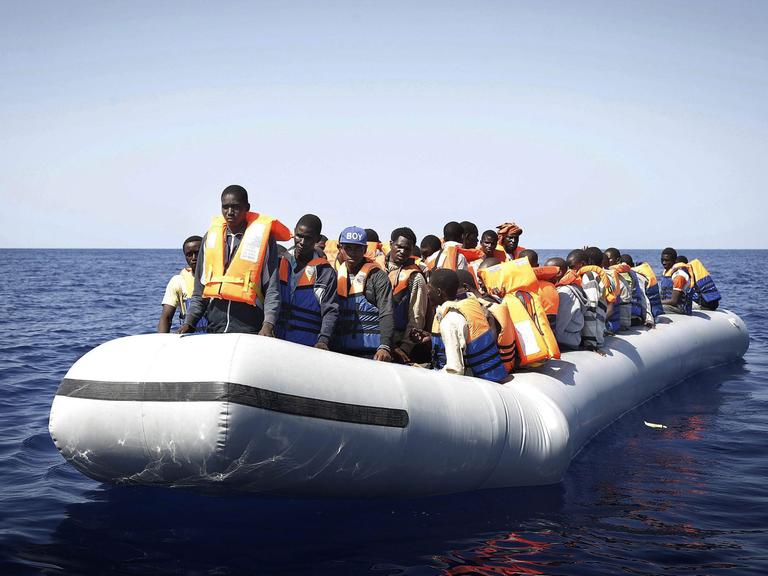 Flüchtlinge aus Afrika stehen in einem Schlauchboot, das im Mittelmeer treibt - sie werden schließlich von einem italienischen Rettungsschiff geborgen.