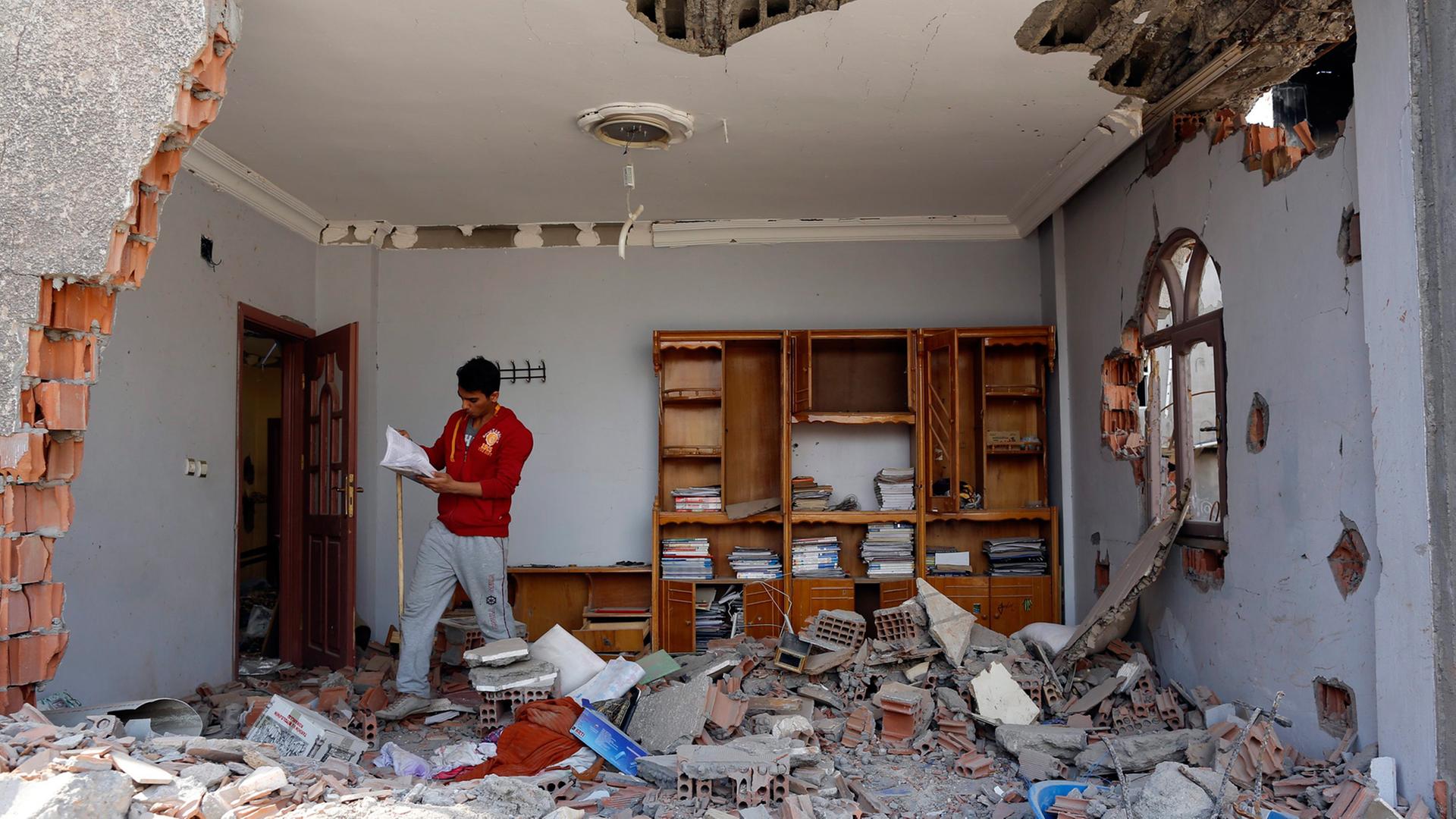 Ein kurdischer Mann schaut sich in seinem zerstörten Haus in der anatolischen Stadt Cizre um. Hier kämpfen türkische Regierungstruppen gegen PKK-Einheiten; Aufnahme vom 3. März 2016