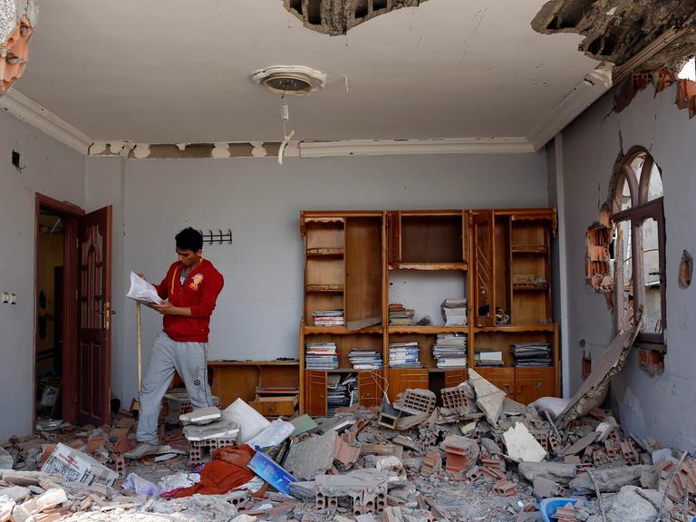 Ein kurdischer Mann schaut sich in seinem zerstörten Haus in der anatolischen Stadt Cizre um. Hier kämpfen türkische Regierungstruppen gegen PKK-Einheiten; Aufnahme vom 3. März 2016