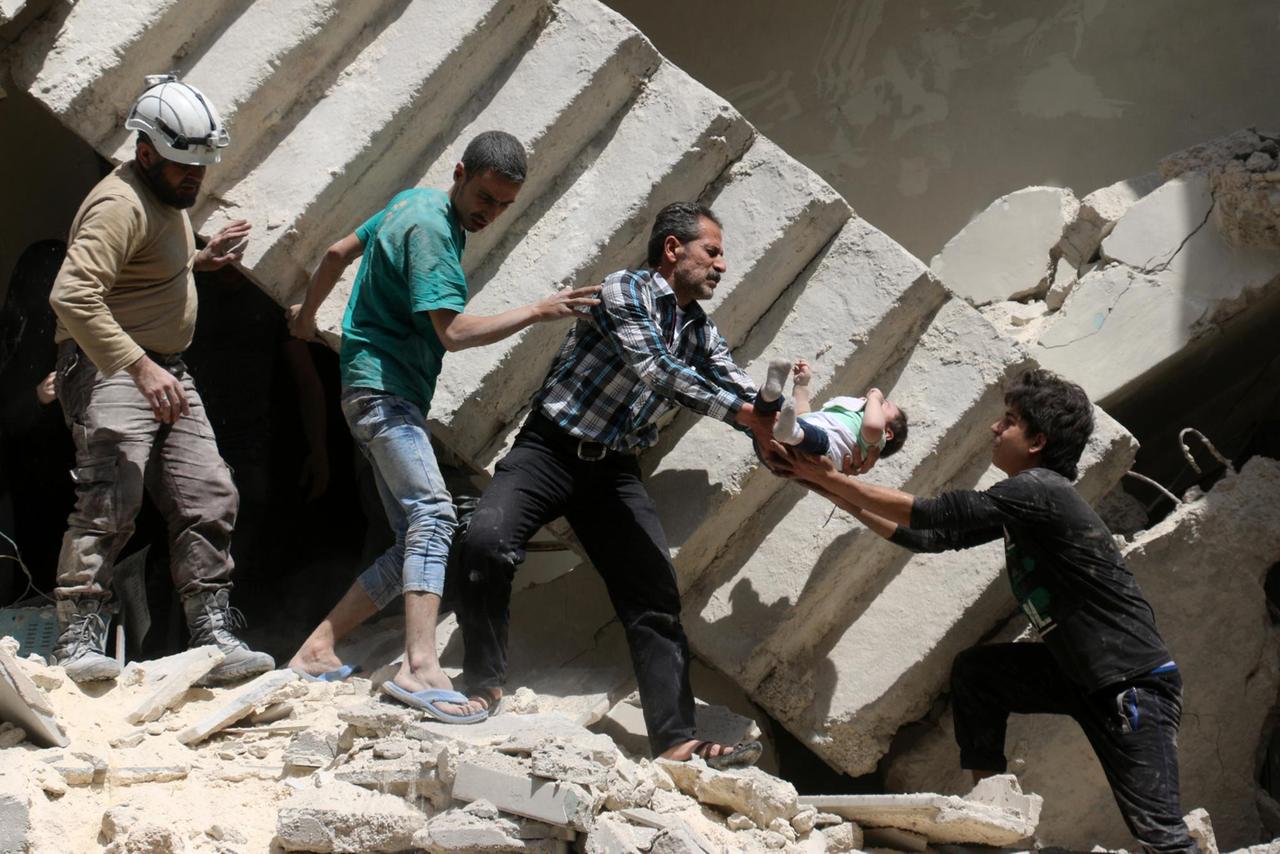 Helfer tragen ein Kind aus den Trümmern nach Luftangriffen auf Aleppo.