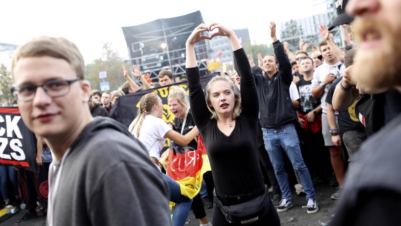 Eine junge Frau formt mit ihren Händen ein Herz über ihrem Kopf auf dem #wirsindmehr-Festival in Chemnitz.