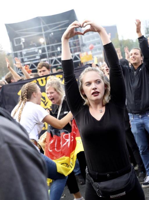 Eine junge Frau formt mit ihren Händen ein Herz über ihrem Kopf auf dem #wirsindmehr-Festival in Chemnitz.
