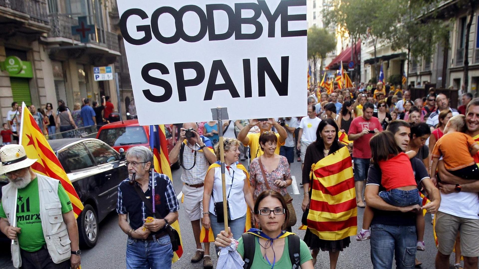Demonstranten mit den katalanischen Farben auf einer Straße. Auf einem Schild steht "Goodbye Spain".