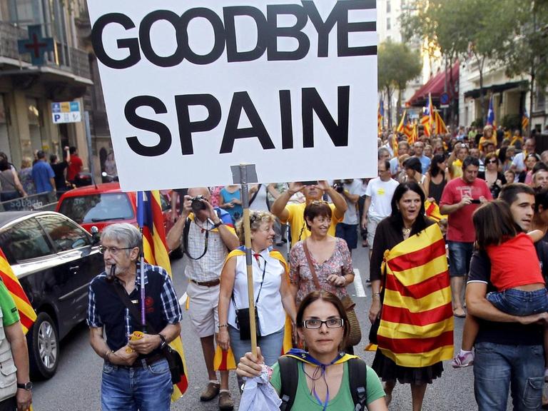 Demonstranten mit den katalanischen Farben auf einer Straße. Auf einem Schild steht "Goodbye Spain".