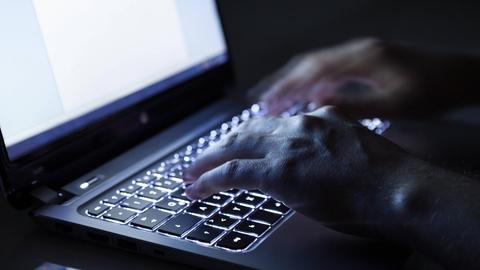 Hände tippen auf einer Computertastatur.