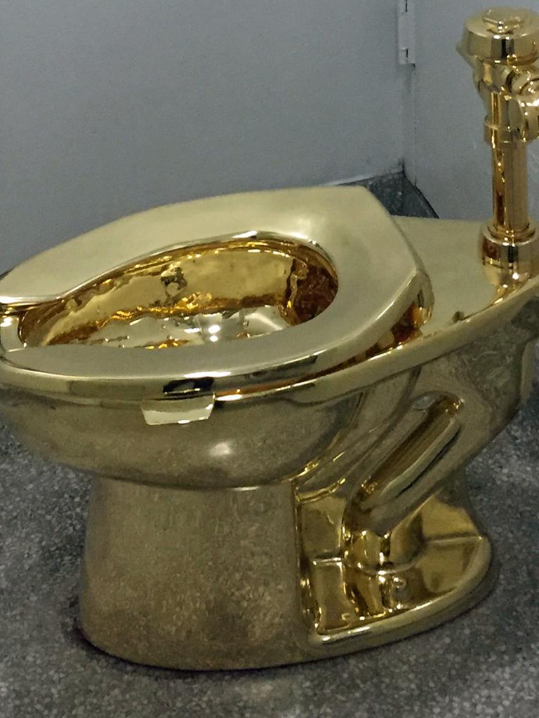 Die Toilette steht in einem kleinen Raum und ist an die Wand angeschlossen.