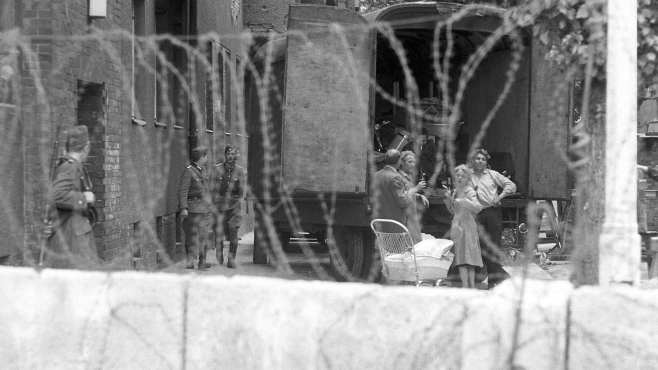 Eine Familie hinter Stacheldraht, bewacht von Volkspolizisten der DDR während der Zwangsräumung von Häusern in der Bernauer Straße in Berlin, 1961. Direkt an der Bernauer Straße verlief die Grenze zwischen West- und Ostberlin.