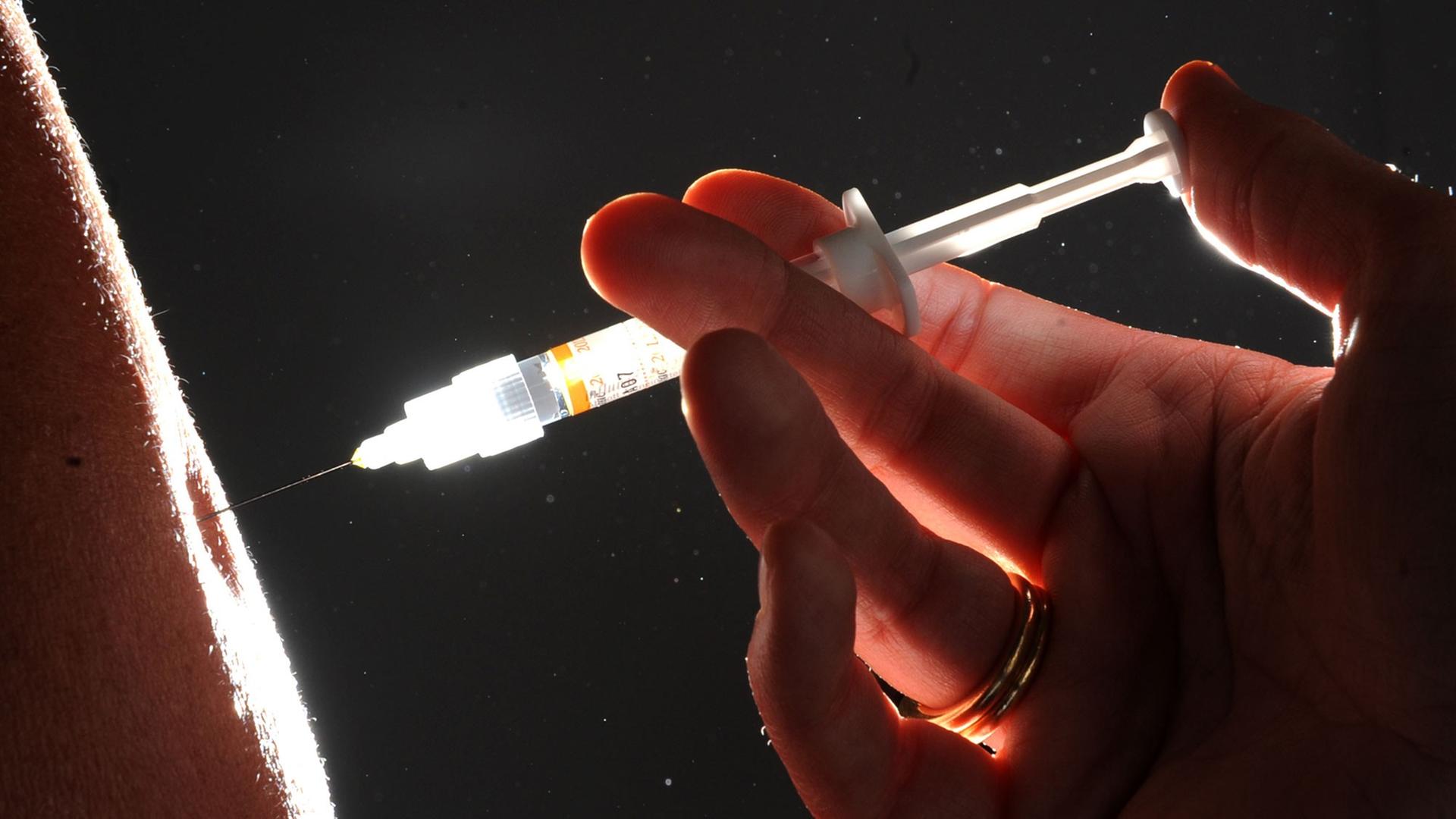 Eine Spritze sticht in einen Arm