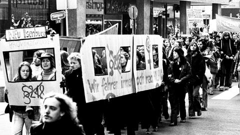 Eine Gruppe hat sich zu einem wandelnden Bus formiert, auf dessen Seite der Schrifttzug steht "Wir fahren immer noch nach Holland". Gemeint sind damit Fahrten zu Abtreibungen in die Niederlande, wo der Eingriff nicht strafbar ist.
