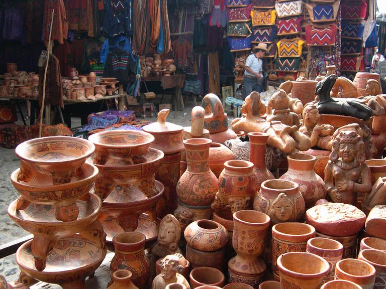 Blick auf traditionelle Tonwaren und Textilien auf einem Markt in Chichicastenango in Guatemala