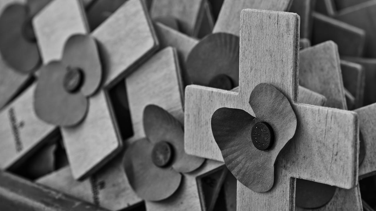 Holzkreuze mit einer stilisierten Blüte erinnern an die Toten