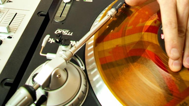 Ein DJ an Turntables