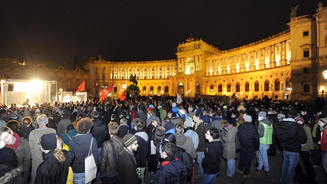 Hunderte Demonstranten bei Nacht vor der erleuchteten Wiener Hofburg.