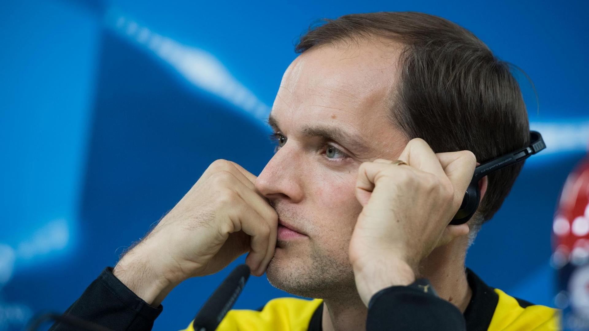 Borussia Dortmunds Trainer Thomas Tuchel hört auf einer Pressekonferenz konzentriert einer Übersetzung über einen Kopfhörer zu. Borussia Dortmunds Trainer Thomas Tuchel hört auf einer Pressekonferenz konzentriert einer Übersetzung über einen Kopfhörer zu.