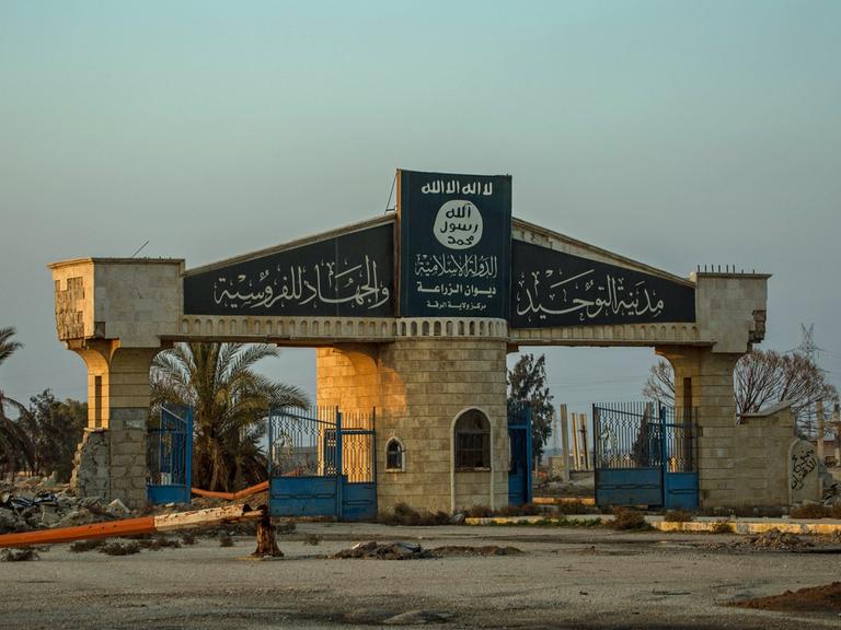 Auf einer Toreinfahrt eines zerbombten Areals in der Region um Rakka in Syrien ist das Logo der vertriebenen Terrormiliz Islamischer Staat zu sehen.