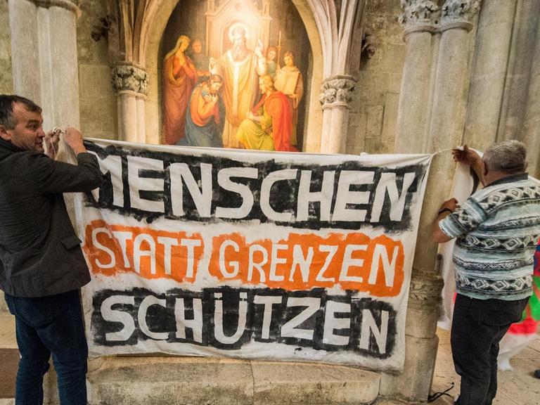  Flüchtlinge hängen am 06.07.2016 im Dom St. Peter in Regensburg (Bayern) ein Transparent mit der Aufschrift "Menschen statt Grenzen schützen" auf.