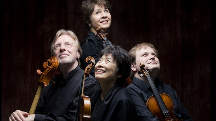 Die zwei Männer und zwei Frauen des Quartetts halten ihre Instrumente im Arm und schauen nach oben.