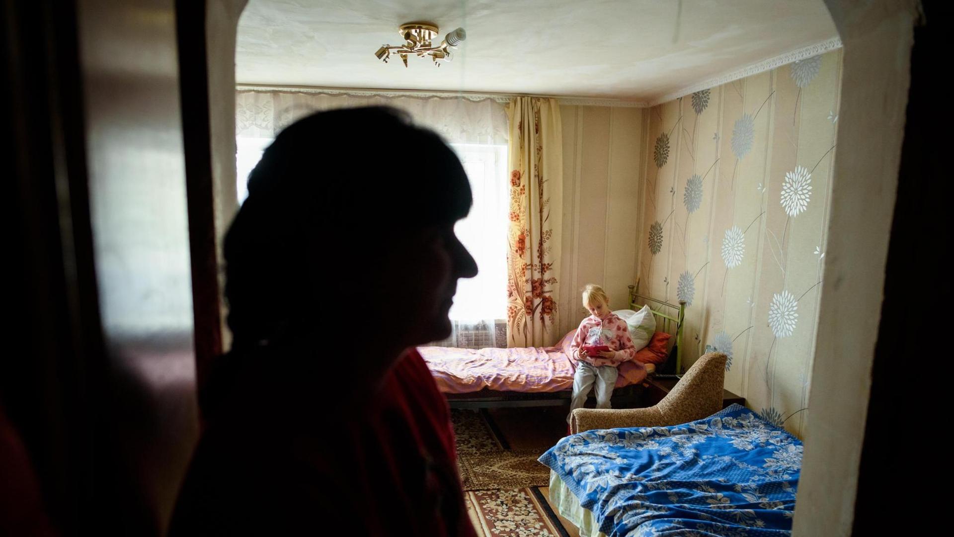 Kira Romanowa spielt im Haus der Familie in einem Dorf in der Nähe von Slowjansk in der Ostukraine und wird dabei von ihrer Mutter Nadeschda Romanova beobachtet.