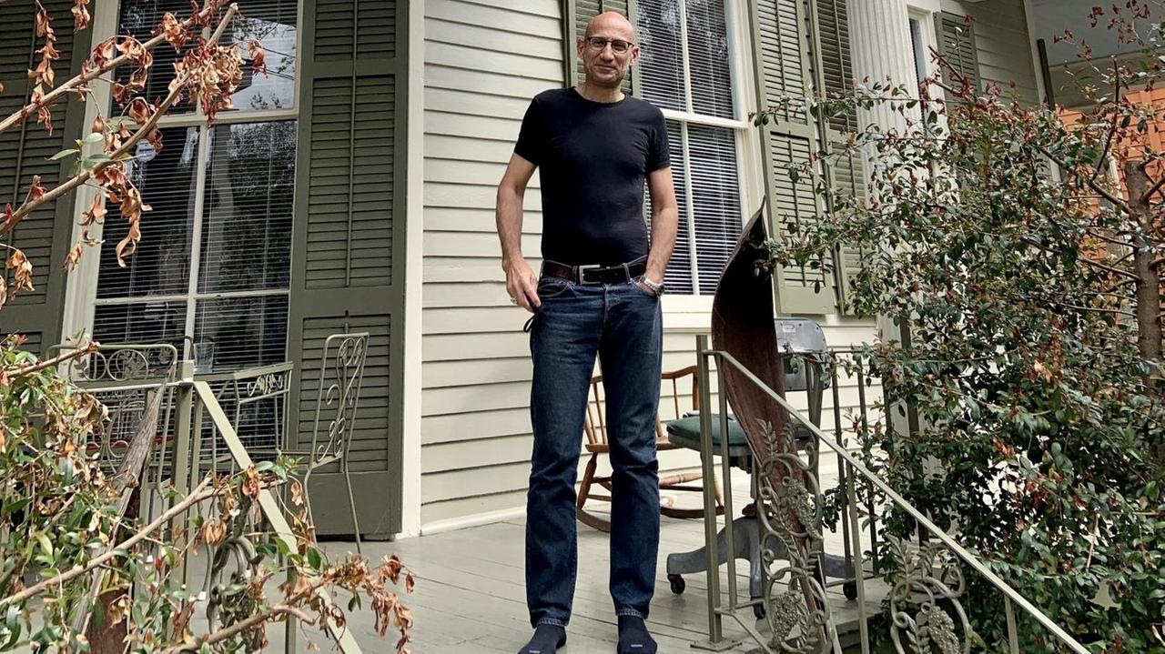 Ein Mann steht auf der Veranda eines Hauses.