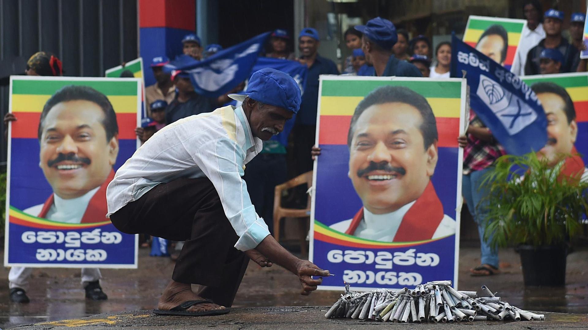 Ein Mann ist in Sir Lanka vor dem Wahlplakat des früheren Staatschefs Mahinda Rajapaksa zu sehen.