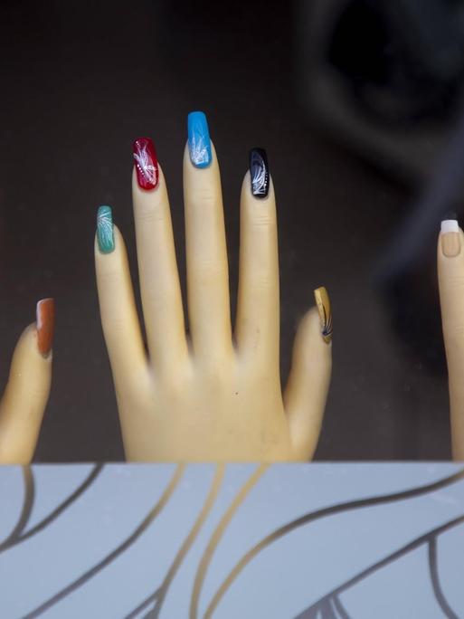 Auslage in einem Nagestudio, bunte Fingernägel an Händen von Schaufensterpuppen