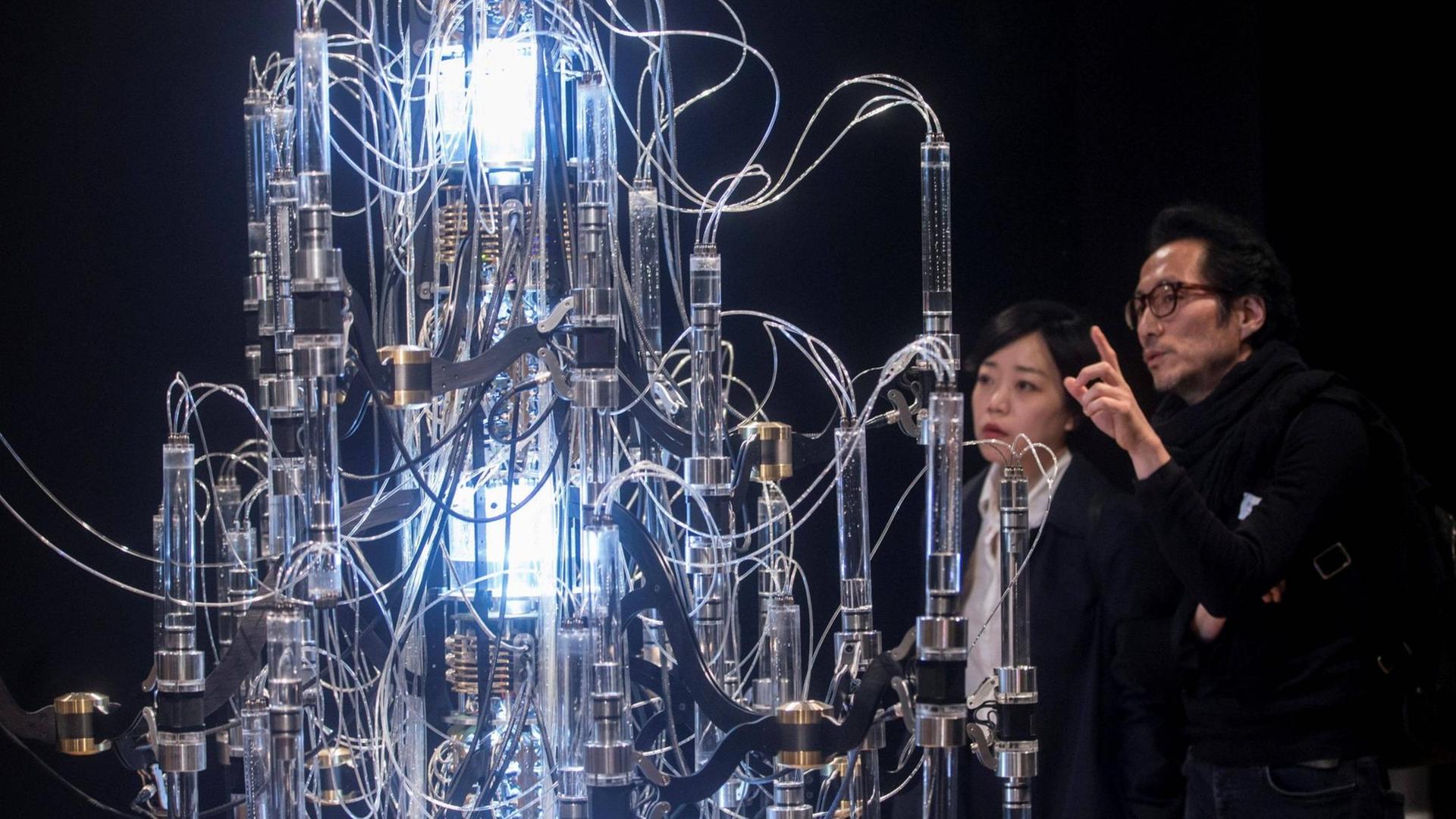 Der koreanische Künstler Yunchul Kim (rechts) und eine Frau schauen sich auf einer Ausstellung sein Werk "Cascada" an