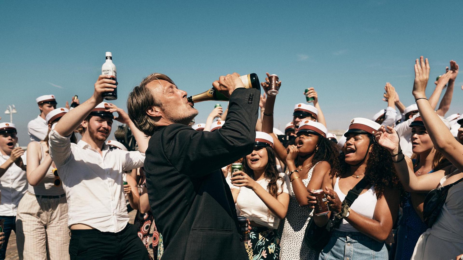 Der Schauspieler Mads Mikkelsen in einem Szenenfoto von Thomas Vinterbergs Film "Der Rausch". Mikkelsen trinkt aus einer Champagnerflasche.