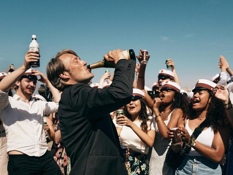 Der Schauspieler Mads Mikkelsen in einem Szenenfoto von Thomas Vinterbergs Film "Der Rausch". Mikkelsen trinkt aus einer Champagnerflasche.