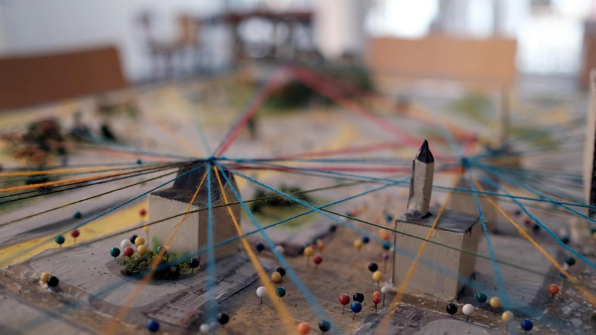 Stadtmodell, über das bunte Fäden gespannt sind.