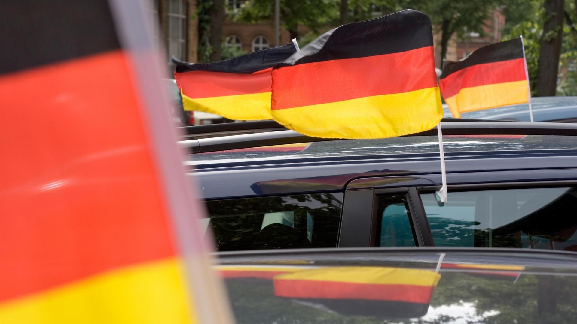 Deutschland-Fahnen wehen an fahrenden Autos.